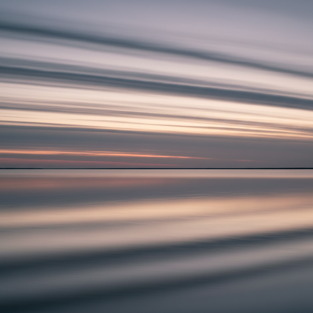 A panoramic view of a distant horizon under a muted twilight sky, with slender stratiform clouds stretching in parallel over a shimmering, minimalist body of water. The surface of the water mirrors the muted greys and dusty mauves of the clouds above, creating a seamless transition between sky and earth. The entire scene is bathed in the gentle, indirect glow of twilight, producing soft, diffuse reflections and subtle shadow gradations. Captured from a wide, eye-level angle, the composition emphasizes horizontal lines and balance, imparting a contemplative, almost abstract mood. The photographic style remains minimalist and elegant, reflecting the refined tone of the site.